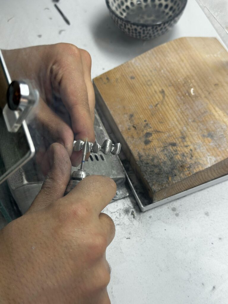 Close-up of a jeweler crafting a silver ring, emphasizing detailed handwork.
